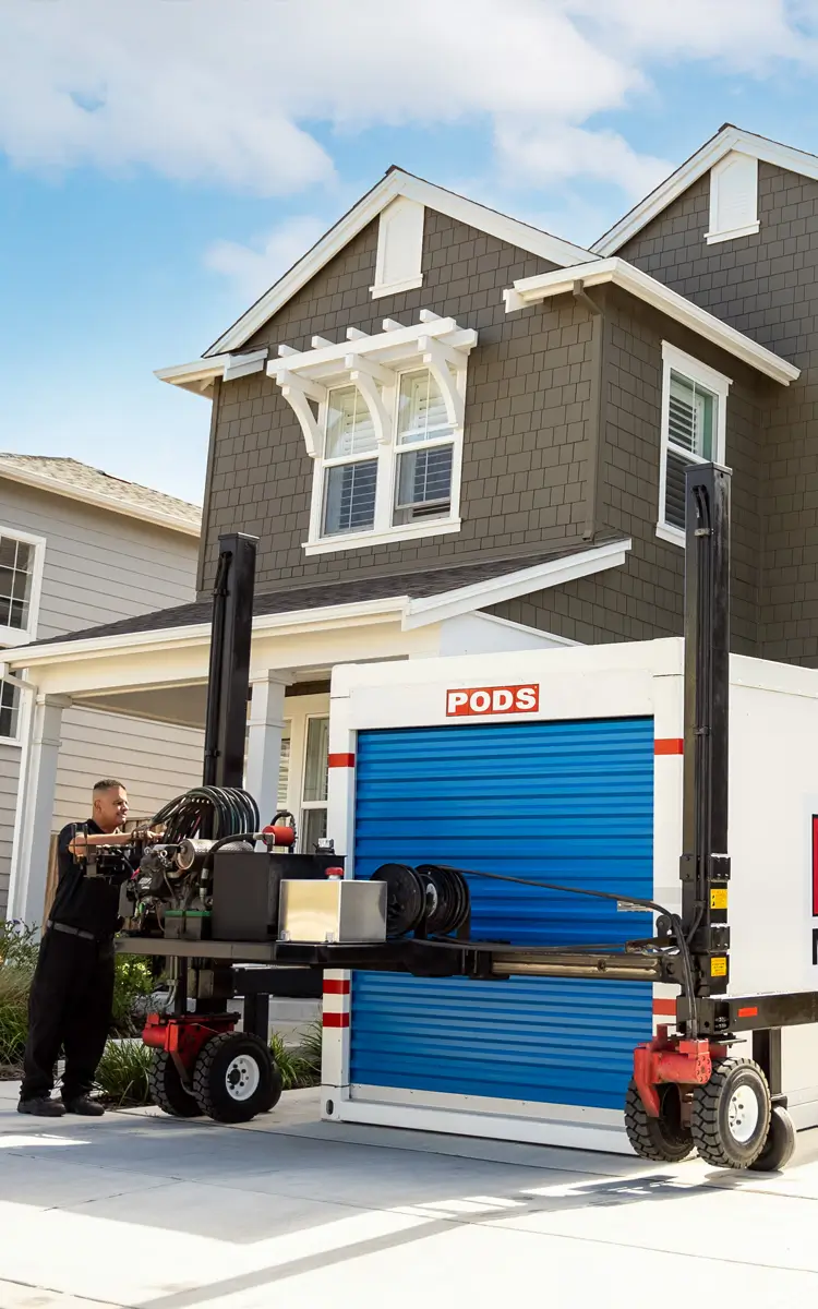A man placing a PODS container in a driveway