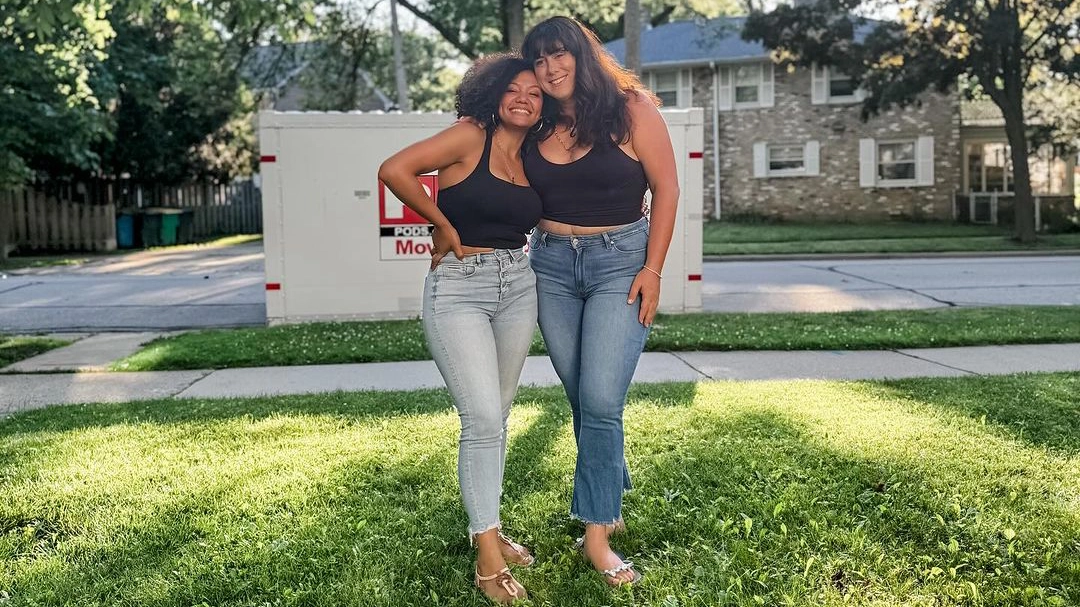 Two customers pose in front of a PODS container from their lawn