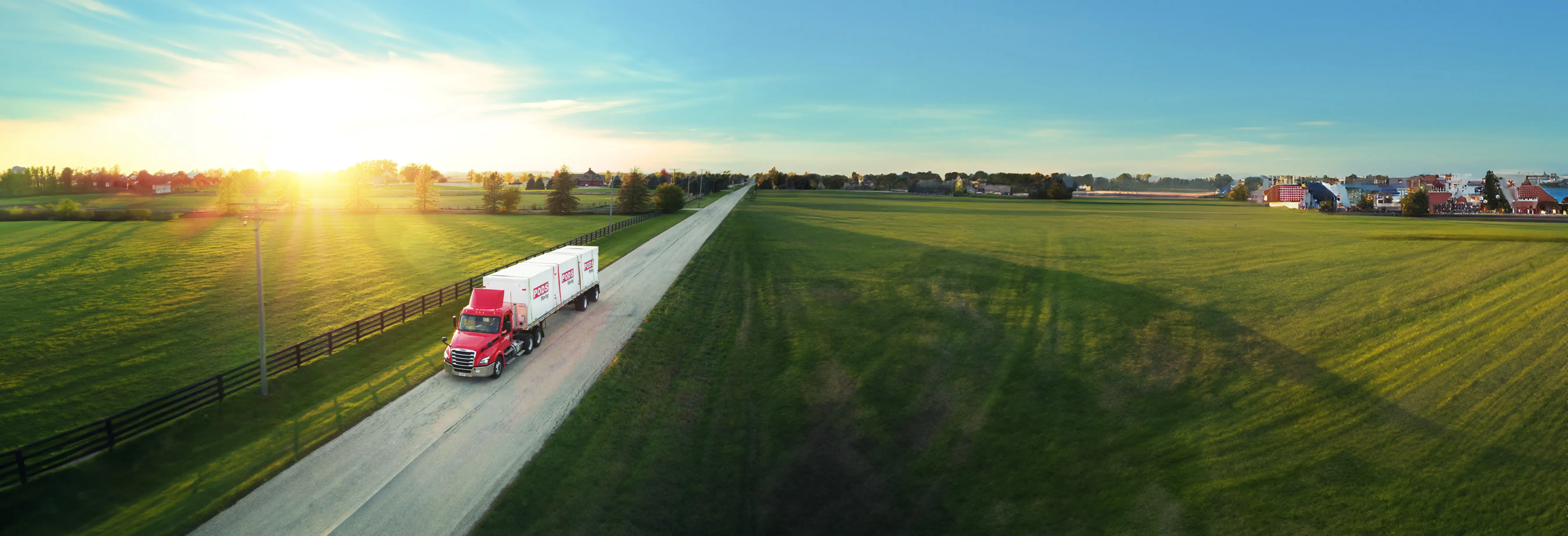 A PODS semi truck driving through farmland on a country road