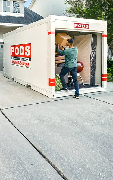 A man packs a box into a PODS container