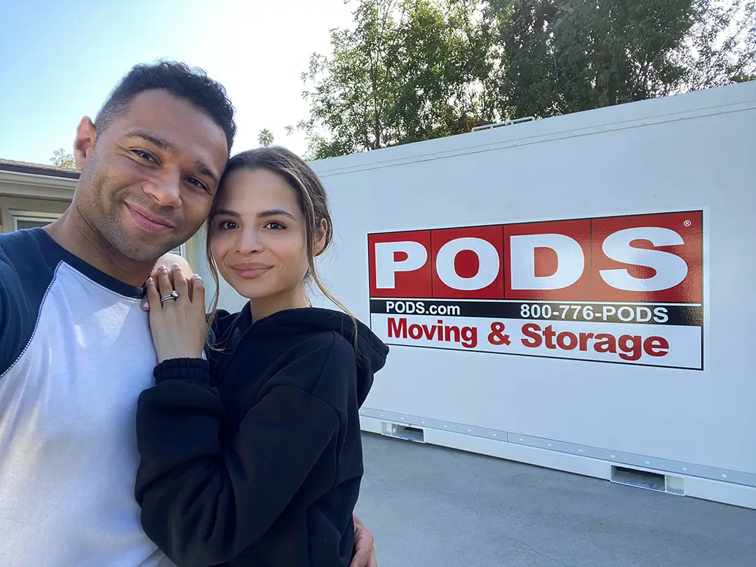 A couple poses in front of a PODS container