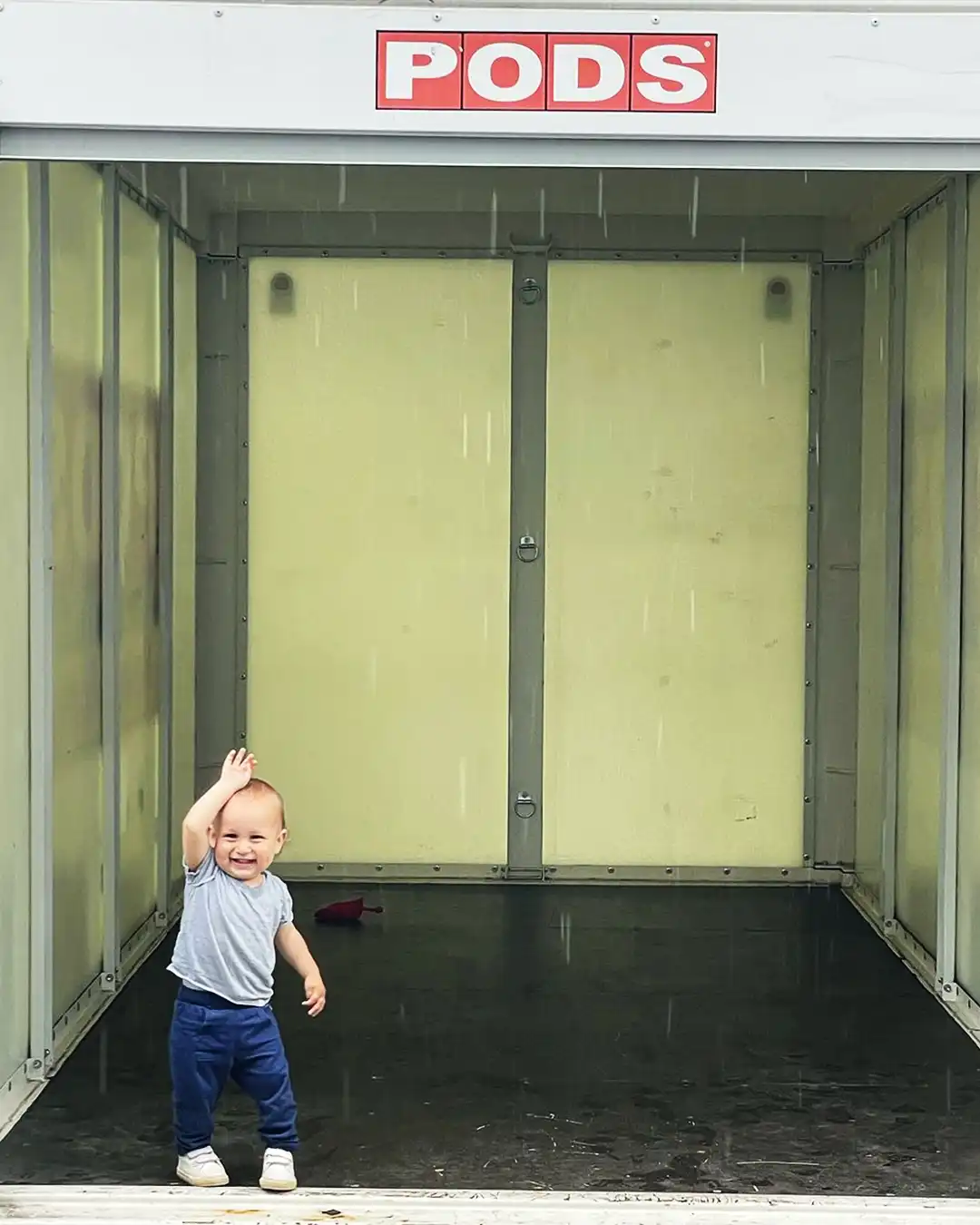 A small child poses inside of an empty PODS container